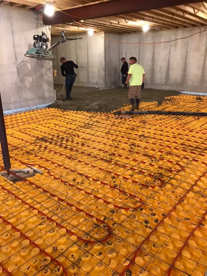 Crew pouring a basement slab over radiant heat tubing